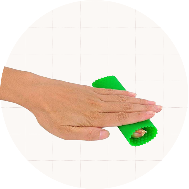 A hand rolling the Sinnsally Garlic Peeler, which is a silicone tube that peels off the skins.