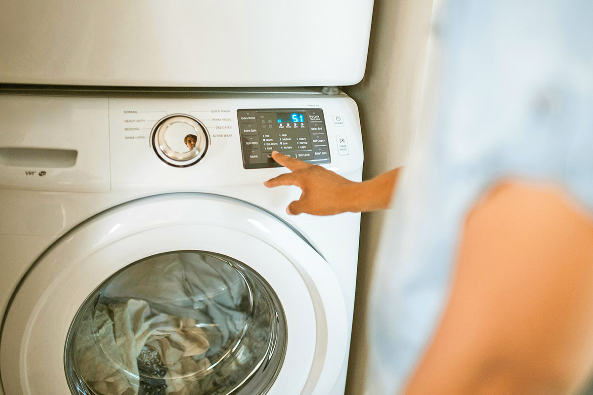 Anonymous person pressing one of the setting buttons on their laundry machine to begin a cycle.