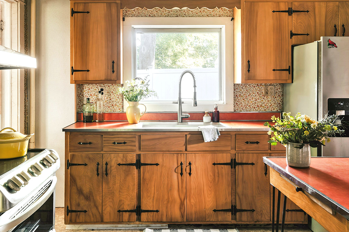 A retro-style all wood kitchen with oversized hinges on the cabinets and red countertops.