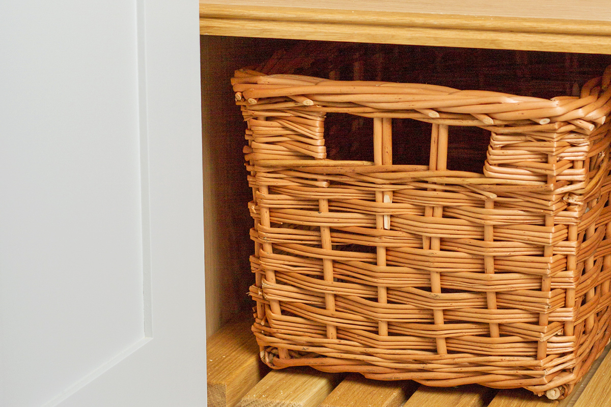 A woven storage bin on a shelf in a closet.