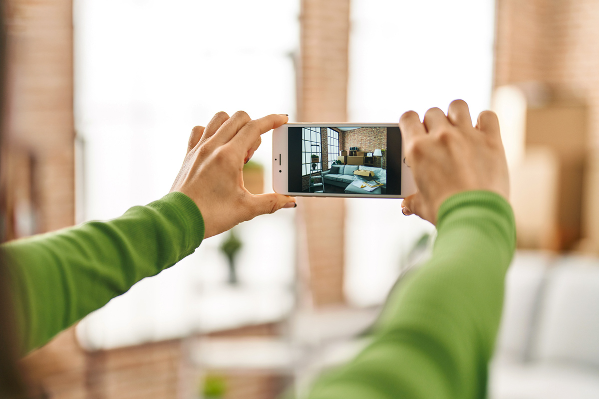 Anonymous person taking photos of a living room on their cell phone.