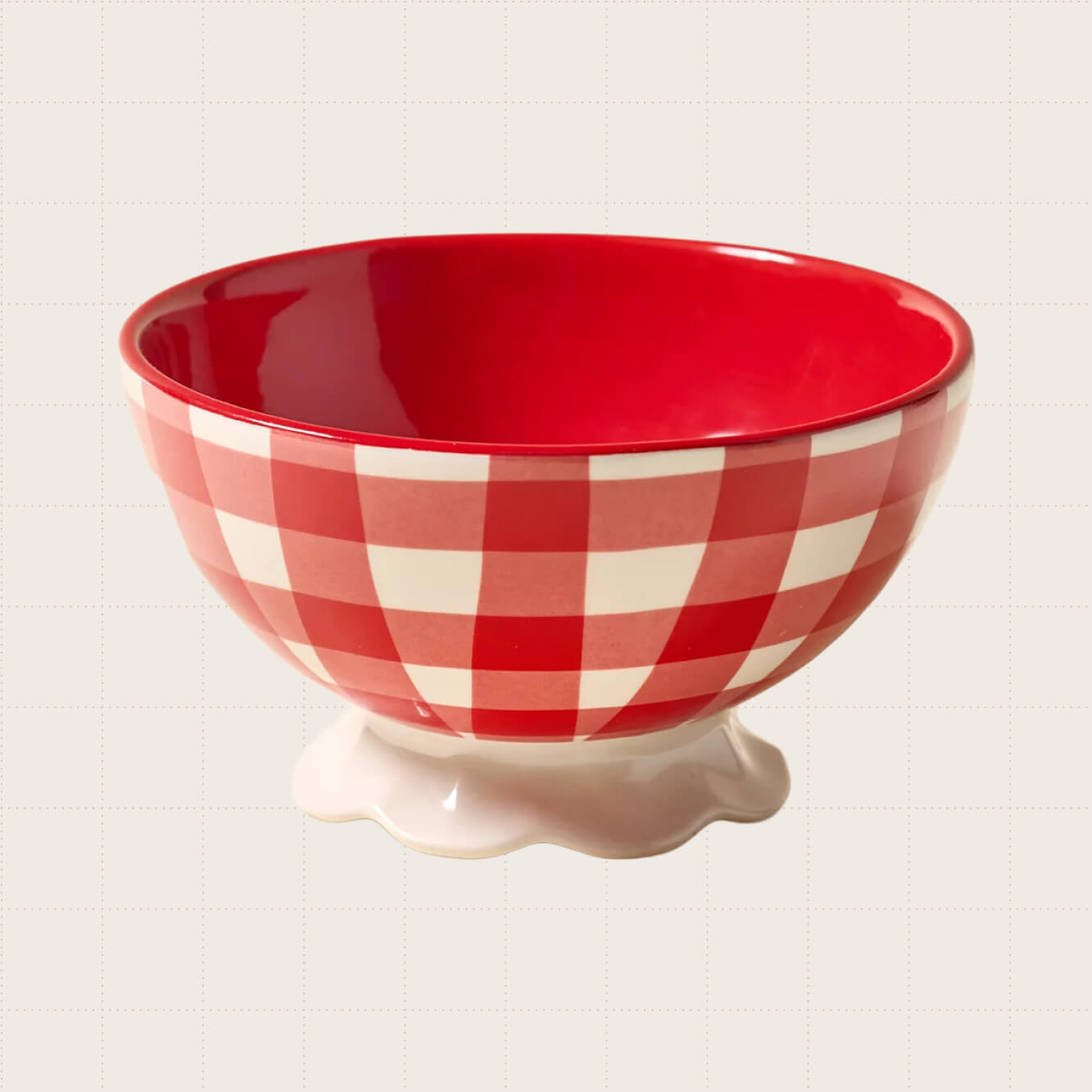 Courtney Ceramic Patterned Pedestal Snack Bowl from Urban Outfitters. It's shown in a red and white gingham pattern and has a round, wavy base.